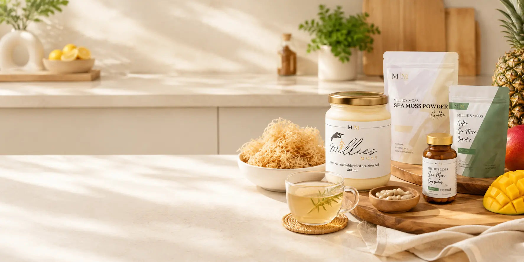 Millie’s Moss sea moss wellness products displayed on a bright kitchen counter with raw sea moss, herbal tea and fresh fruit.