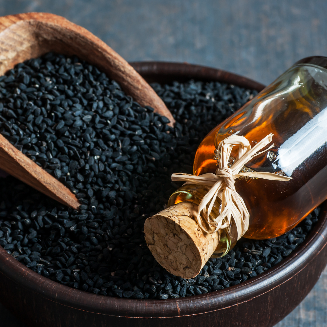 Bottle of black seed oil resting on a bed of Nigella sativa seeds, known for its powerful antioxidant, anti-inflammatory, and immune-supporting properties.