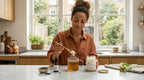 Woman adding sea moss gel to a warm herbal tea with black seed oil on a kitchen counter