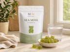 Millie’s Moss Apple Sea Moss Gummies pouch with green gummies and a glass of water on a kitchen counter.