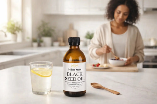 Millie’s Moss black seed oil bottle next to lemon water during a healthy morning wellness routine in the kitchen.