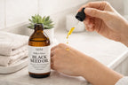 Dropper applying black seed oil onto skin for natural skincare and hydration.