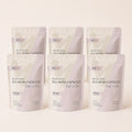 Six-pack bundle of Millie's Moss Purple Sea Moss Capsules on a warm off-white background.