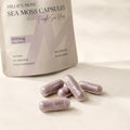 Close-up of Millie’s Moss Purple Sea Moss Capsules showing purple capsules in front of the product pouch.