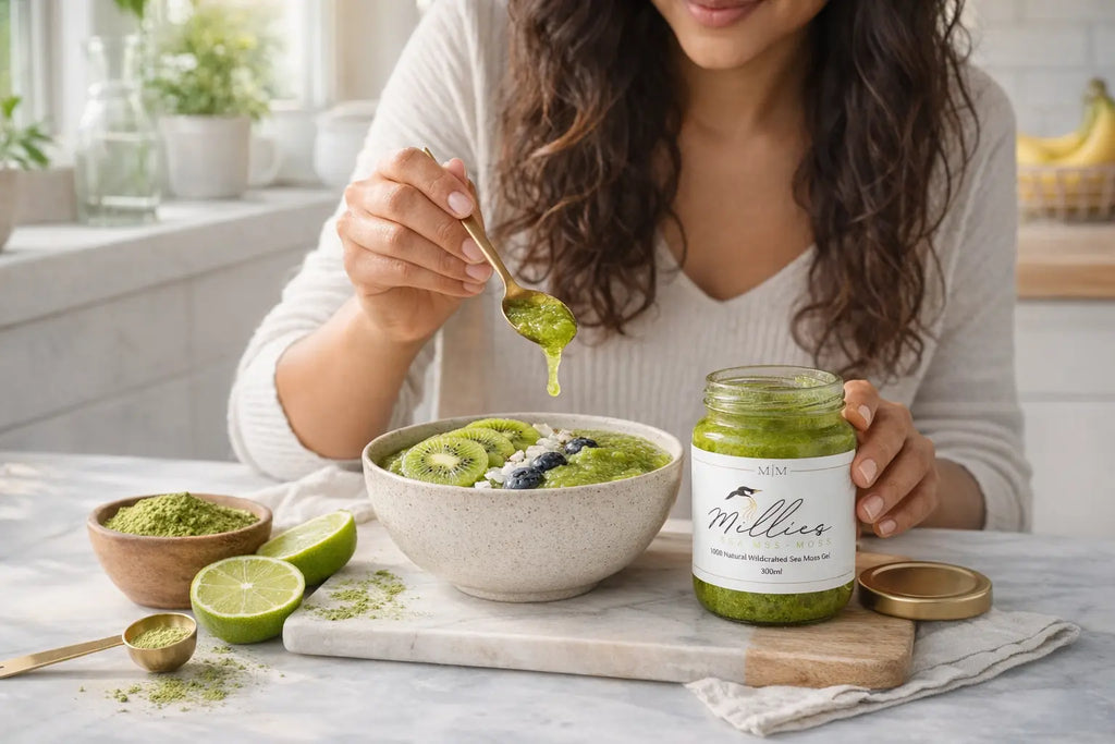 Woman adding matcha sea moss gel to smoothie bowl with kiwi blueberries and superfood toppings