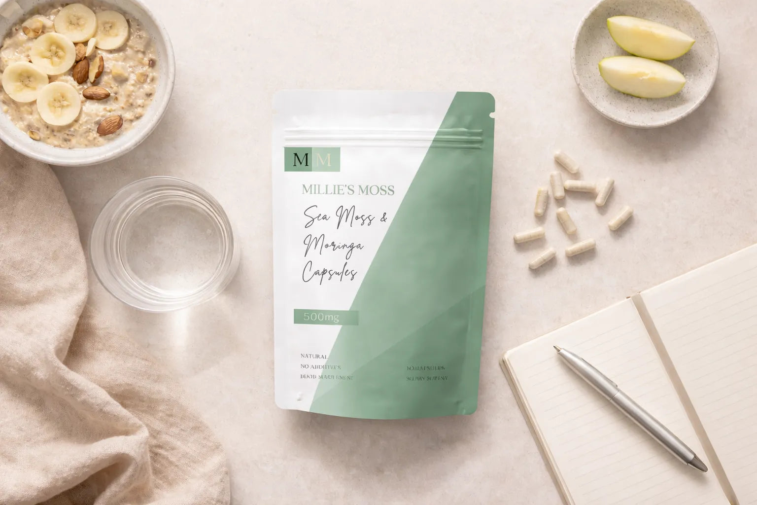 Flat lay of sea moss and moringa capsules with breakfast bowl, apple slices, and notebook for a daily wellness routine.