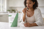 Woman taking birdock root capsules with water as part of a healthy daily supplement routine.
